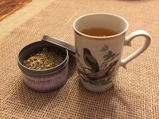 Photo of tea cup filled with herbal comfort hot tea; tin of herbal comfort tea shown