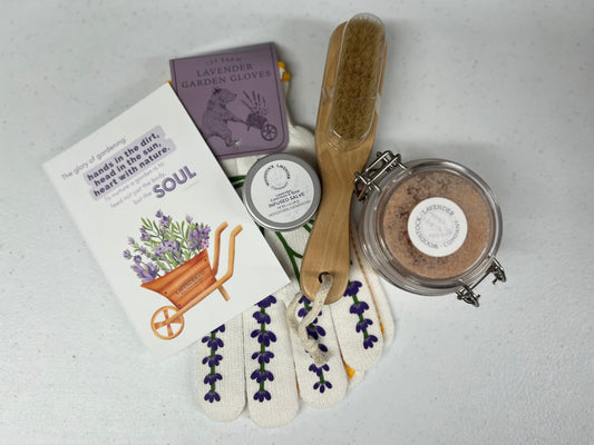Some items from our subscription box, including a gardening guide, gardening gloves, our lavender salve, a sugar scrub, and a lavender brush.